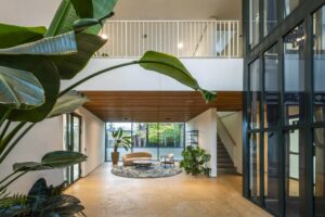 Moderne, lichte ontvangsthal aan de De Cuserstraat met zithoek, grote planten en glazen lift.